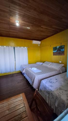two beds in a room with yellow walls at Pousada Bosque dos Aruãs in Salvaterra
