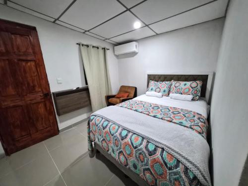 a bedroom with a bed and a chair at Ciudad Merliot, casa Don Pablo in Hacienda Plan de La Laguna