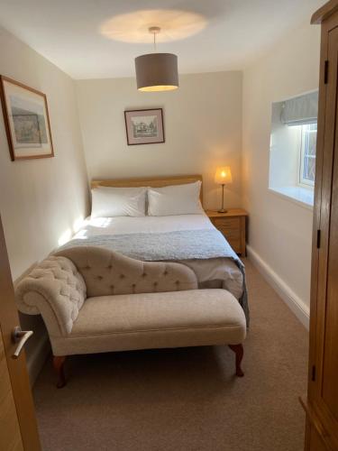 a bedroom with a large bed with a tufted foot board at The Bothy in Lyndhurst