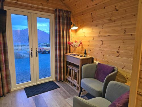 a room with a desk and chairs and a window at Rowan Gorgeous Glamping Hideaway in Durnamuck