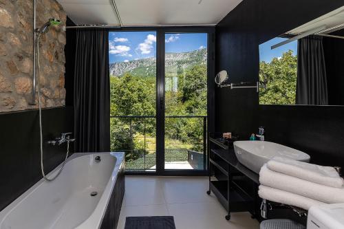 a bathroom with a tub and a sink and a window at Villa Arija in Grižane