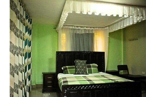 a bedroom with a bed with green walls and a window at Mamboleo princely Homes in Kisumu