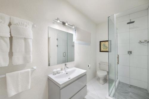 a white bathroom with a sink and a shower at Coconut Court Beach Hotel in Bridgetown