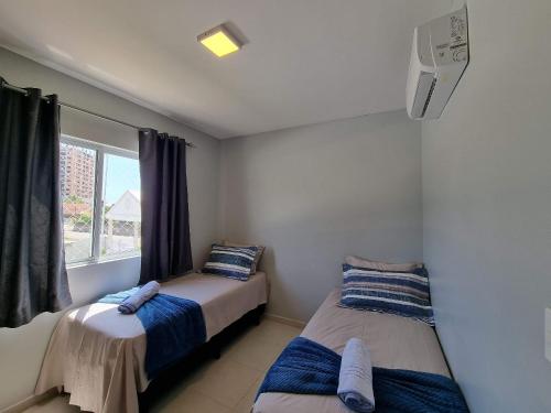 two beds in a room with a window at Curta Praia do Quilombo - Palladium in Penha
