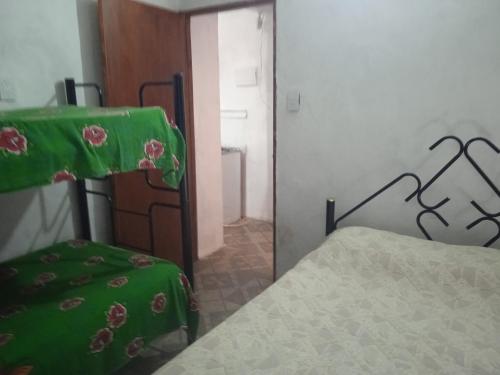 a bedroom with a bed with a green blanket on it at Los Cali 27 planta alta 1 in Balneario Buenos Aires