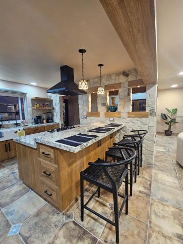 a kitchen with a large island with stools and a stove at Casa Flor del Desierto in Loreto