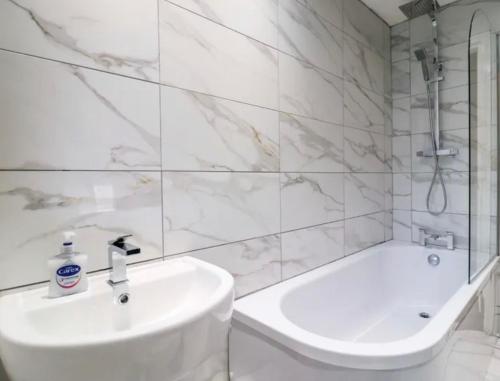 a white bathroom with a sink and a bath tub at High Tide in Whitstable