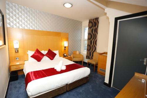 a hotel room with a large bed with red pillows at Acorn Lodge Hotel Gatwick & Parking in Horley