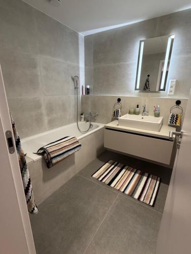a bathroom with a sink and a tub and a mirror at Sky Park by MISSONI in Nivy