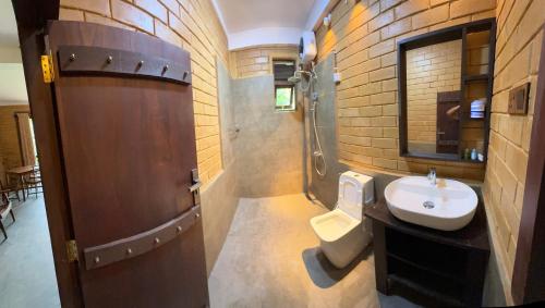 a bathroom with a sink and a toilet at Rainforest Royal Heritage in Deniyaya