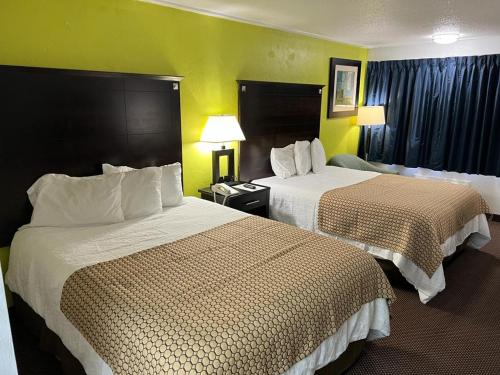 two beds in a hotel room with yellow walls at Driftwood Inn - Lake City in Lake City