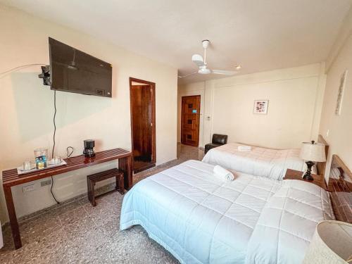 a hotel room with two beds and a flat screen tv at Casa Delfin in Playa del Carmen