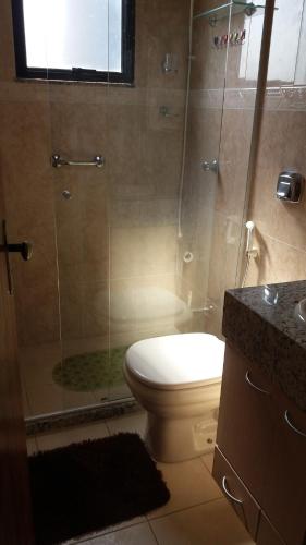 a bathroom with a toilet and a glass shower at Lindo Flat no Centro de Caxambu in Caxambu