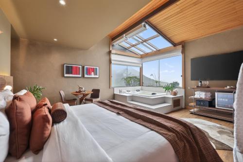 a bedroom with a large bed with a tub and a window at Siramat Hotel in Petrópolis