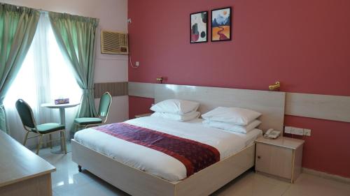 a bedroom with a bed with a red wall at Hotel Summersands Al Wadi Al kabir in Muscat