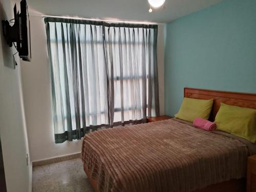 a bedroom with a bed with yellow pillows and a window at Hotel Mi Casa Mata II in Morelia