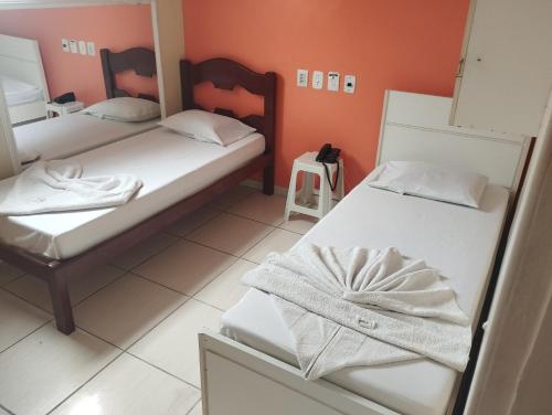 two beds in a room with orange walls at Motel pousada Zafira in Salvador