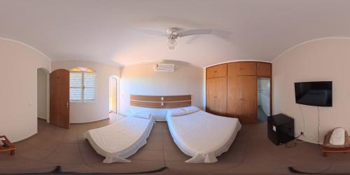a large room with two beds and a tv at Hotel Nova Sorocabana in Brodósqui