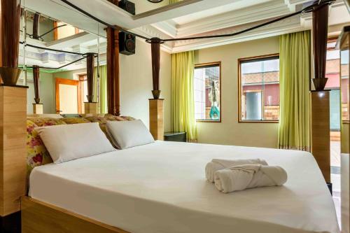 a large white bed in a room with windows at Status Motel in Serra
