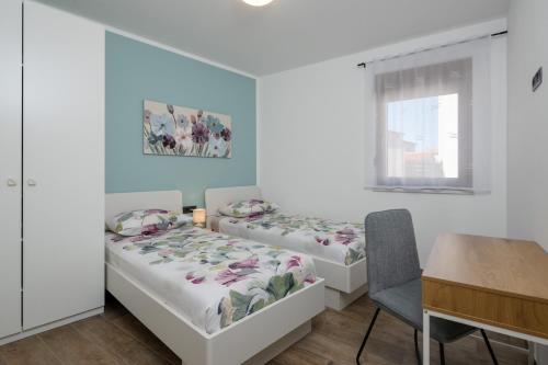 two beds in a room with a table and a desk at House Hana 2415 in Vodnjan