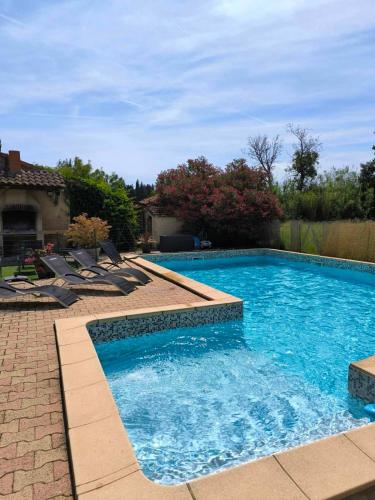 a large swimming pool with lounge chairs in a yard at La barque aux Romarins in Orange