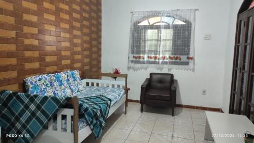 a bedroom with a bed and a chair and a window at House Duque de Caxias in Duque de Caxias