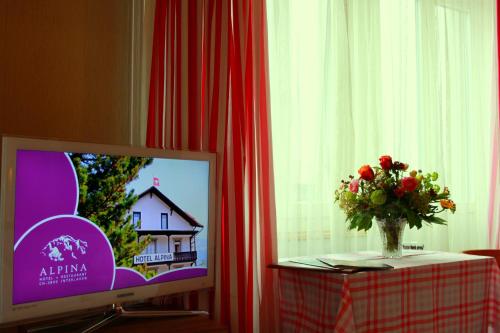 a vase of flowers on a table next to a television at Alpina Hotel in Interlaken