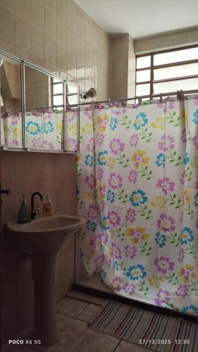 a bathroom with a shower curtain with a sink at House Duque de Caxias in Duque de Caxias