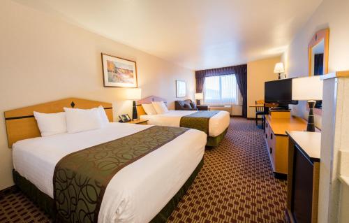 a hotel room with two beds and a desk at Crystal Inn Hotel & Suites - Great Falls in Great Falls