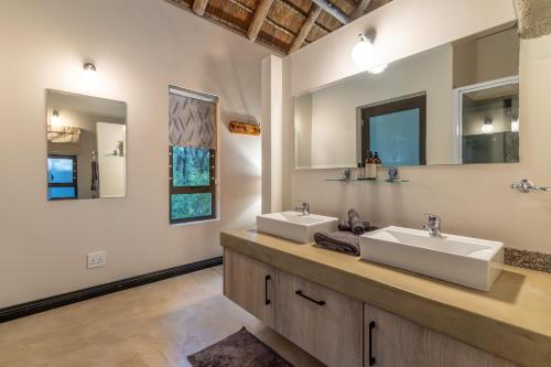 a bathroom with two sinks and two mirrors at Phelwana Game Lodge in Hoedspruit