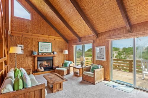 a living room with a fireplace and a wooden ceiling at 1245 - Castle Sween in Corolla