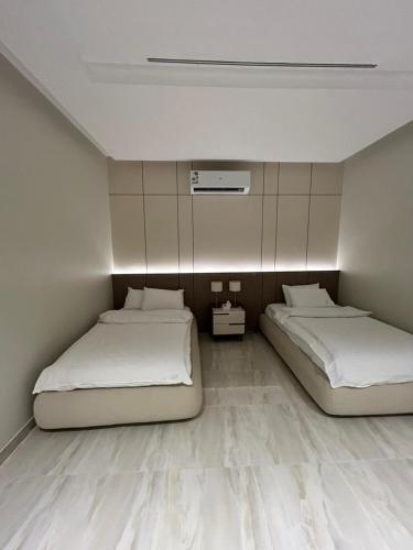 two beds in a room with white walls at IN 2 Chalet in Jeddah