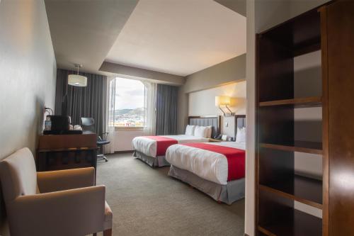 a hotel room with two beds and a window at Best Western Plus Santa Cecilia Pachuca in Pachuca de Soto