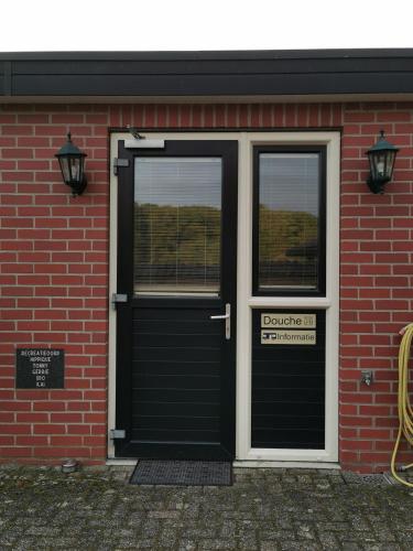 a red brick building with a black door and windows at Recreatieoord Hippique in Westendorp