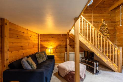 a living room with a couch and a staircase at Walliswood Lodge - Wood Burner, Air Con & Wi-fi, Rural Retreat in Ewhurst