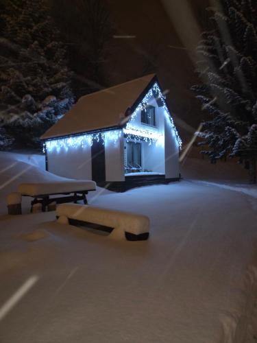a house covered in snow with lights on it at Cerla Korbielów - Domek dla Dwojga in Korbielów