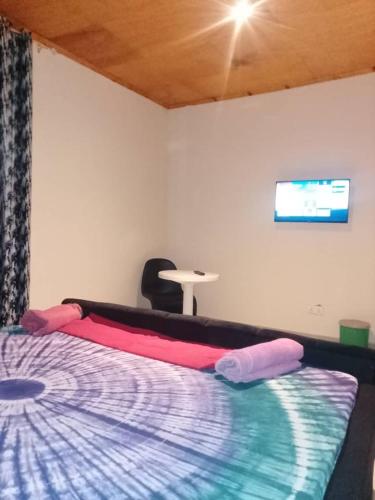 a bedroom with a bed and a tv on the wall at Cutting Edge Guest House in Daranka