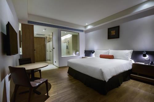 a hotel room with a bed and a table and a desk at Just Sleep Kaohsiung Station in Kaohsiung