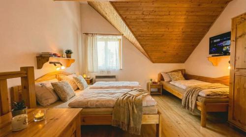 a bedroom with two beds in a room with wooden ceilings at Apartmán 339 - Tatralandia in Liptovský Mikuláš