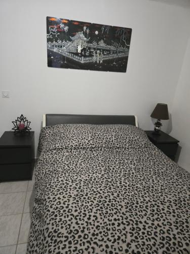a bed with a black and white comforter in a bedroom at Le cocon de mag in Miramas