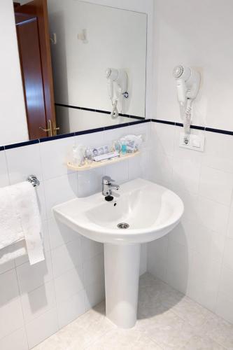 a white bathroom with a sink and a mirror at Hotel Villa del Son in Porto do Son