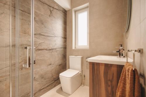 a bathroom with a toilet and a sink and a shower at Seaside Luxury Home with Rooftop Pool in Birżebbuġa