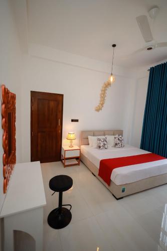 a bedroom with a bed and a table and a stool at Yellow Rose Hotel in Kandy