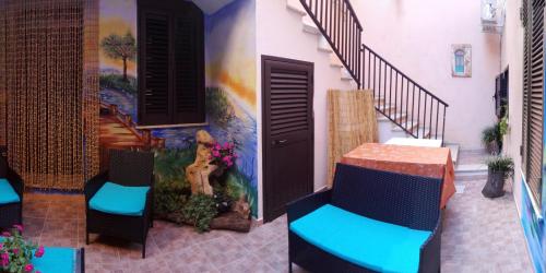 a patio with two chairs and a wall with a painting at B&B Oasi Tepilora in Bitti