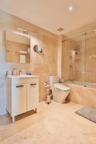 a bathroom with a toilet and a sink and a shower at Modern Ground Level, 4 BR condo in Palm-Eagle Beach
