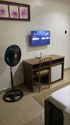 ein Zimmer mit einem Schreibtisch, einem Ventilator und einem Fernseher in der Unterkunft Bolif Hotel in Abeokuta