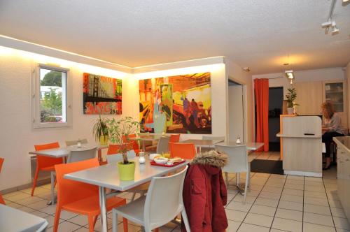 une salle à manger avec des tables et des chaises orange dans l'établissement B Hotel Caen Mondeville, à Mondeville