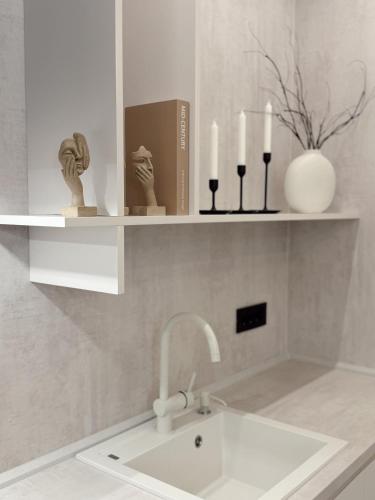 a bathroom with a sink and a shelf with candles at Mediteran Line Apartman 1 in Sombor