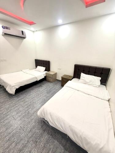 two beds in a room with white walls at شاليهات زارا Zara in Taif