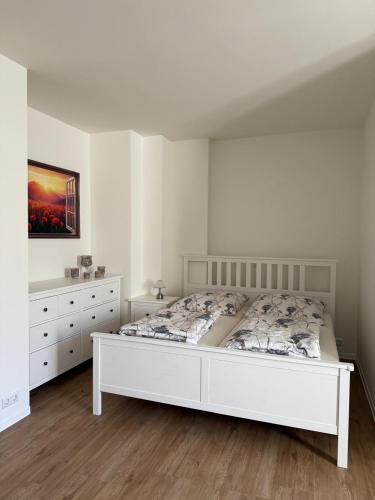 a white bedroom with a bed and a dresser at Kaiserlich schlafen in der alten Post in Oelsnitz